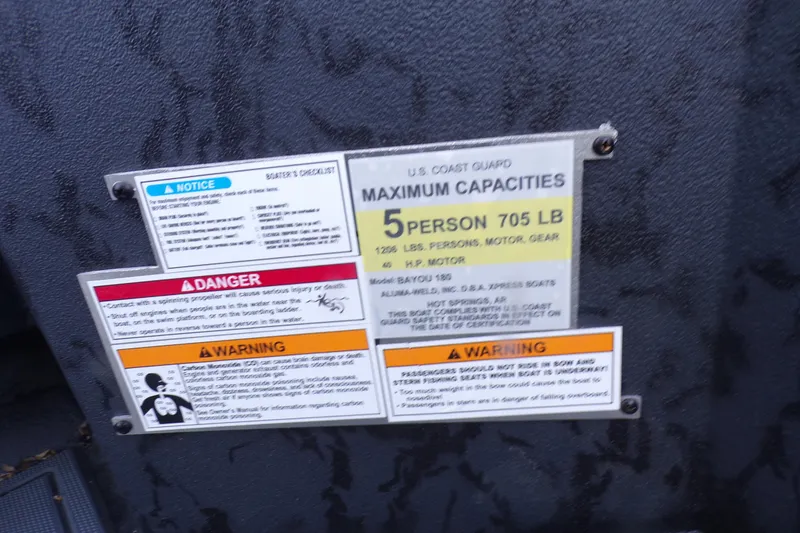 Slide: The Image of 2026 Xpress Bayou 180 capacity and safety warning labels on boat interior. - 5