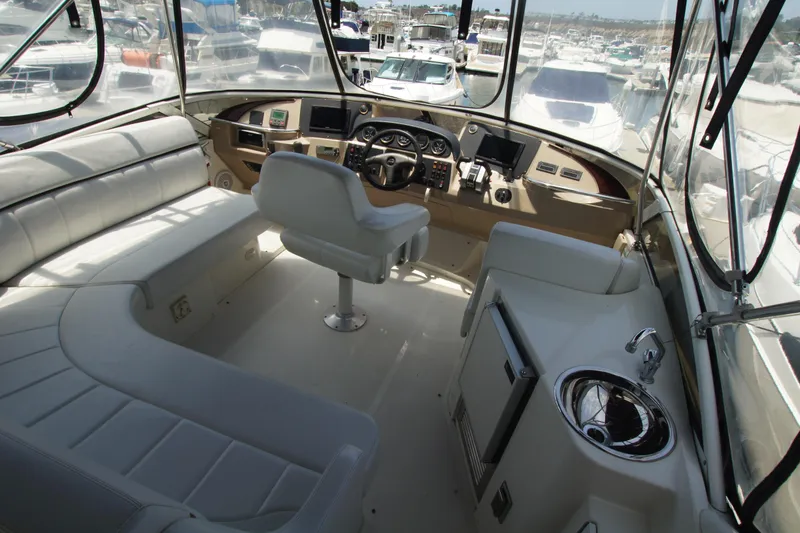 Slide: The Image of 2005 Carver 44 Cockpit Motor Yacht interior with helm, seating, and marina view. - 16