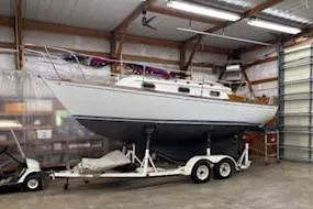 Slide: The Image of 1984 Cape Dory 25D interior with striped seating, wooden cabinetry, and nautical decor. - 15