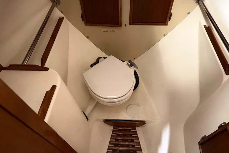 Slide: The Image of 1984 Cape Dory 25D sailboat interior with compact marine toilet and wooden accents. - 20