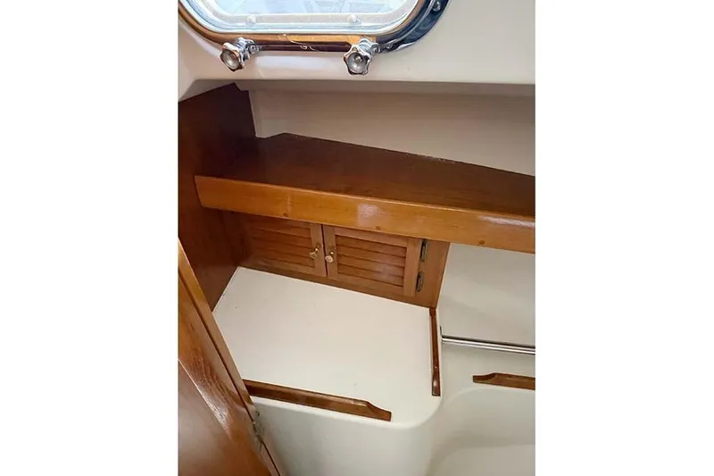 Slide: The Image of 1984 Cape Dory 25D interior with wooden cabinetry and porthole window. - 22