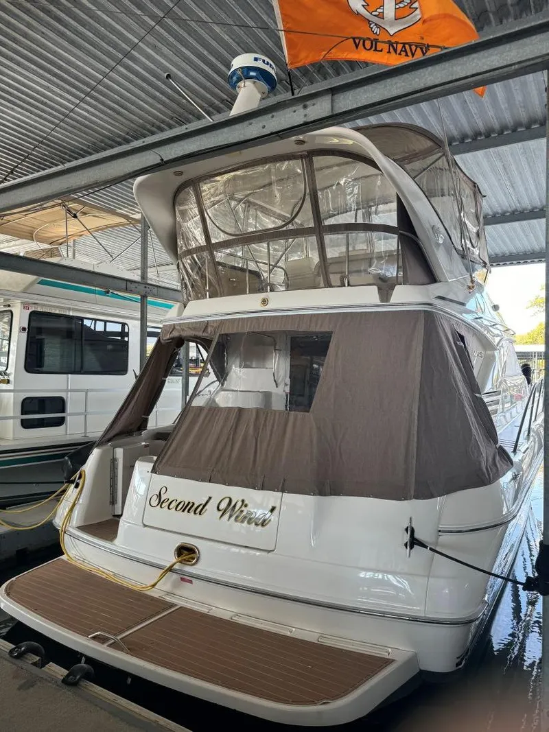 Slide: The Image of 1996 Sea Ray 400 Sedan Bridge docked under shelter, featuring "Second Wind" name. - 10