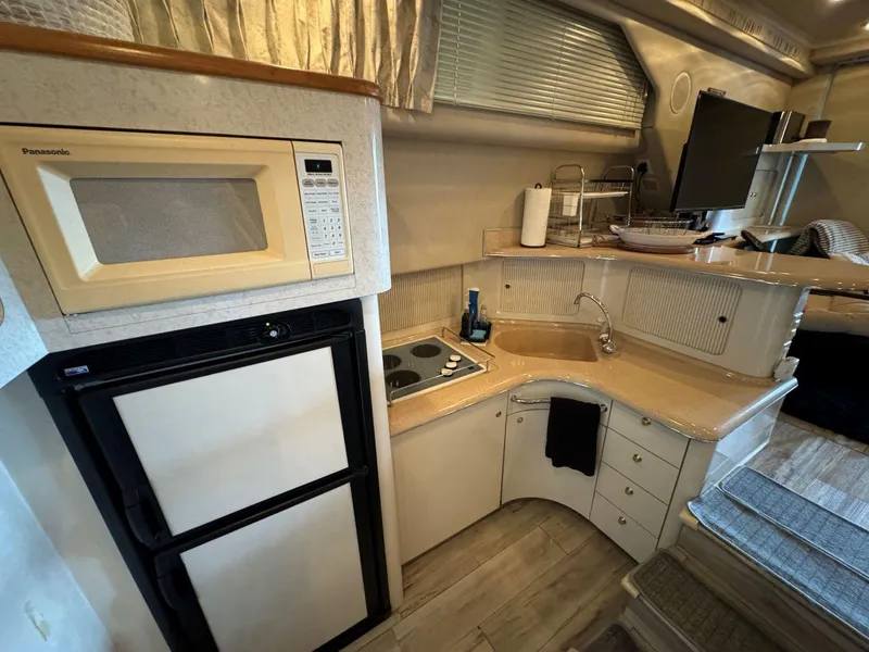 Slide: The Image of 1996 Sea Ray 400 Sedan Bridge kitchen with microwave, fridge, and sink. - 26