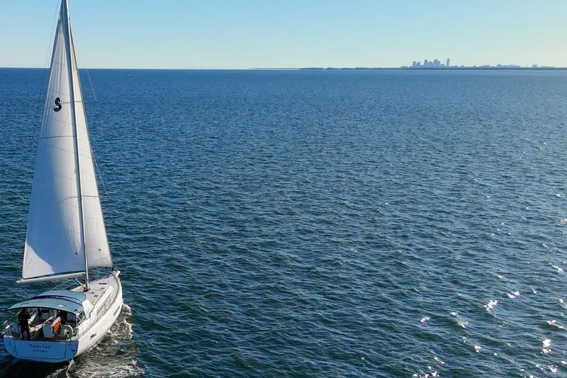 Slide: The Image of Sailboat Beneteau Oceanis 40.1, 2022 model, cruising on open sea with distant city skyline. - 147