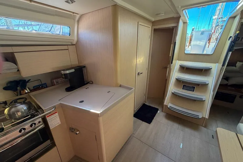 Slide: The Image of Interior of 2022 Beneteau Oceanis 40.1 yacht, featuring modern kitchen and wooden cabinetry. - 4