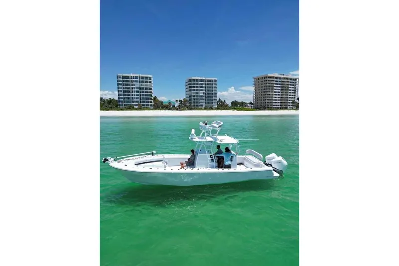 Slide: The Image of 2023 Andros Offshore 32 boat cruising near beachfront buildings on clear turquoise water. - 1