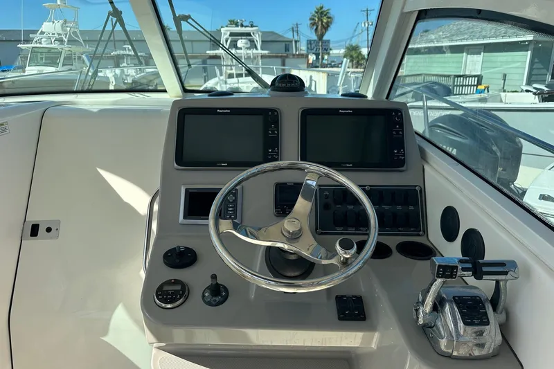 Slide: The Image of Control panel of a 2012 Boston Whaler 315 Conquest boat with steering wheel and navigation screens. - 2