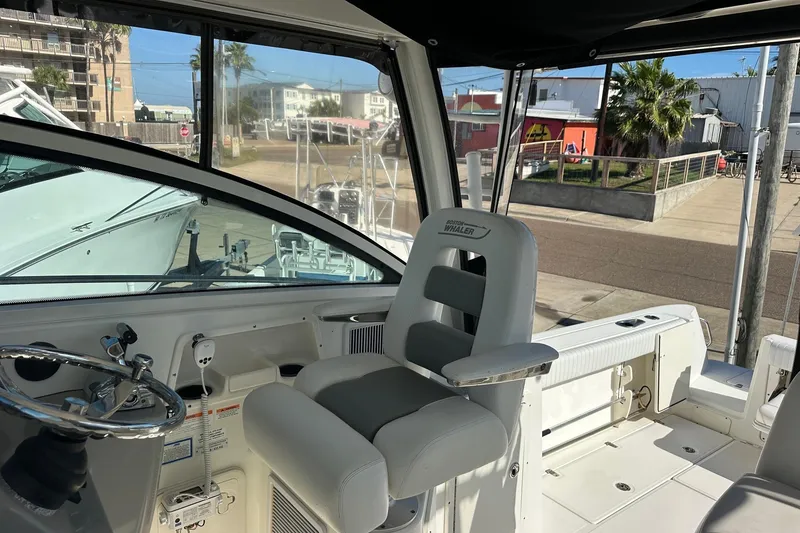 Slide: The Image of Interior of 2012 Boston Whaler 315 Conquest boat, featuring helm and seating area. - 4