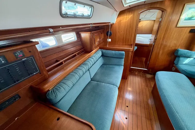 Slide: The Image of Interior of 2000 Beneteau Oceanis 461 yacht with blue seating and wooden finishes. - 12