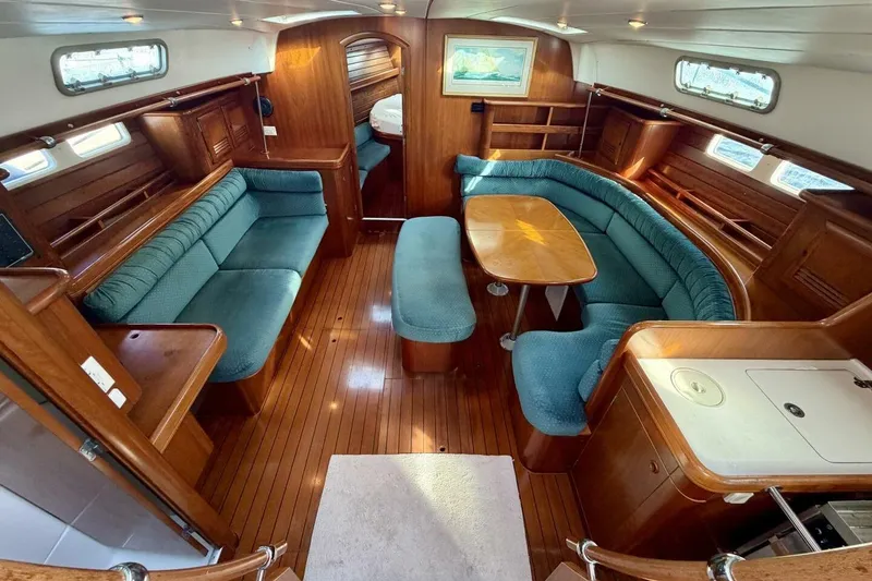 Slide: The Image of Luxurious interior of 2000 Beneteau Oceanis 461 sailboat with wood finish and blue seating. - 2
