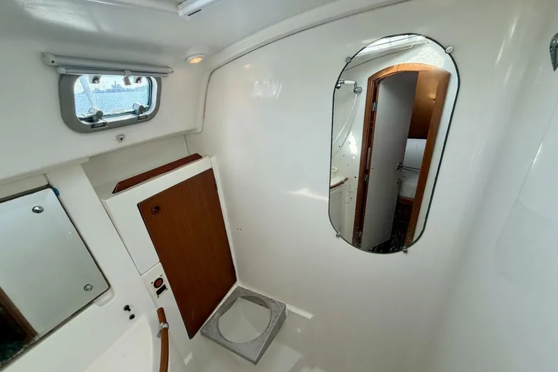 Slide: The Image of Interior of 2000 Beneteau Oceanis 461 yacht, featuring a compact bathroom with mirror and porthole. - 26