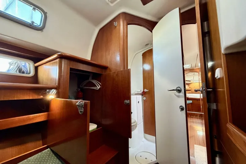 Slide: The Image of Interior of 2000 Beneteau Oceanis 461 yacht, featuring wood cabinetry and compact bathroom. - 31