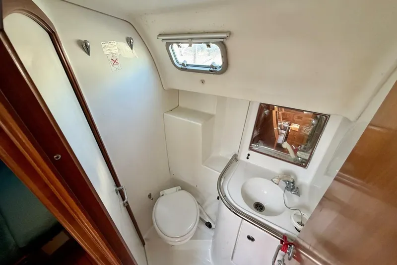 Slide: The Image of Bathroom interior of 2000 Beneteau Oceanis 461 yacht, featuring toilet, sink, and window. - 34