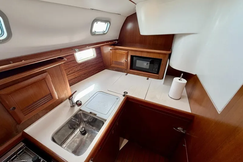 Slide: The Image of Galley kitchen in 2000 Beneteau Oceanis 461 sailboat with wood cabinetry and stainless steel sink. - 39