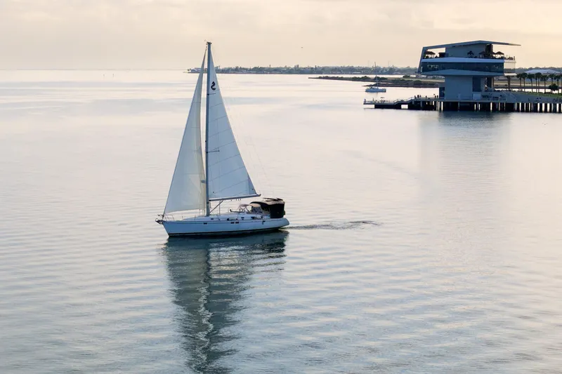 Slide: The Image of Sailboat Beneteau Oceanis 461, 2000 model, cruising near modern waterfront structure. - 88