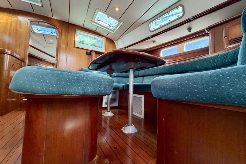 Slide: The Image of Interior of 2000 Beneteau Oceanis 461 yacht with wooden flooring and blue cushioned seating. - 9
