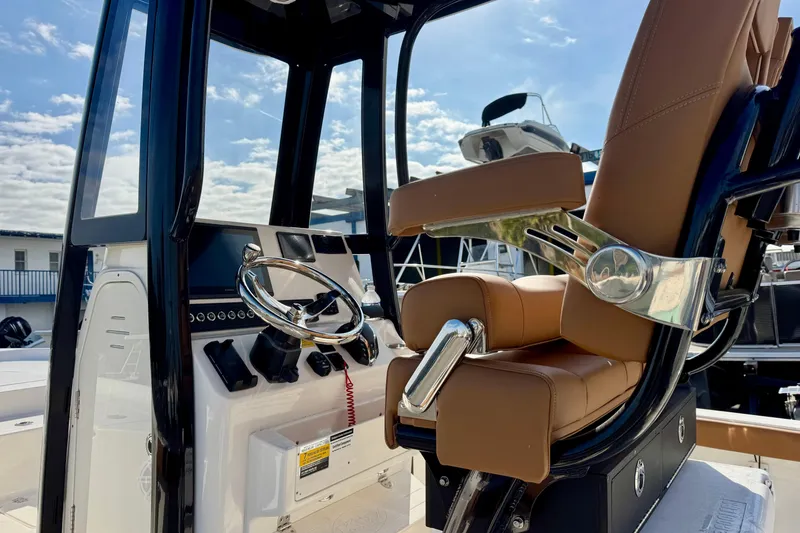 Slide: The Image of 2026 Key West 230 Bay Reef boat interior with steering wheel and brown seating. - 17