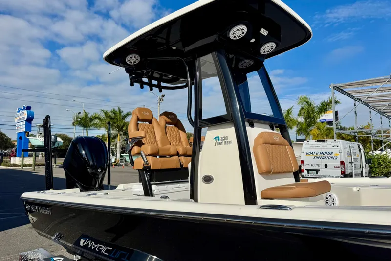 Slide: The Image of 2026 Key West 230 Bay Reef boat with tan seats and black hull, parked outdoors. - 6