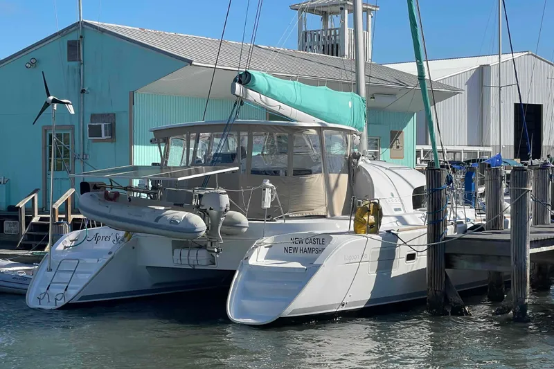 Slide: The Image of 2012 Lagoon 380 S2 catamaran docked at marina, turquoise building in background. - 107
