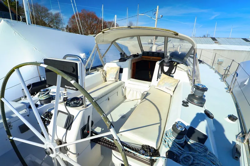 Slide: The Image of 2004 J Boats J/46 sailboat cockpit with steering wheel and seating under blue sky. - 13
