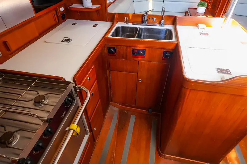 Slide: The Image of 2004 J Boats J/46 yacht kitchen with wooden cabinetry, stove, and double sink. - 28