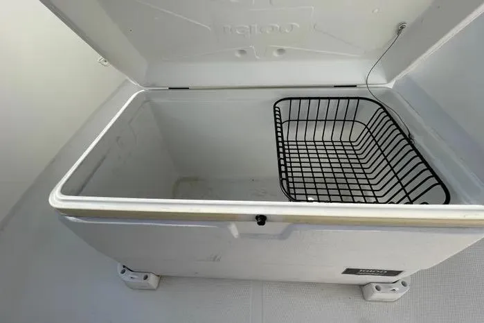 Slide: The Image of Storage compartment with cleaning brushes on a 2004 Kenner Fishmaster Travis Edition 220 boat. - 48