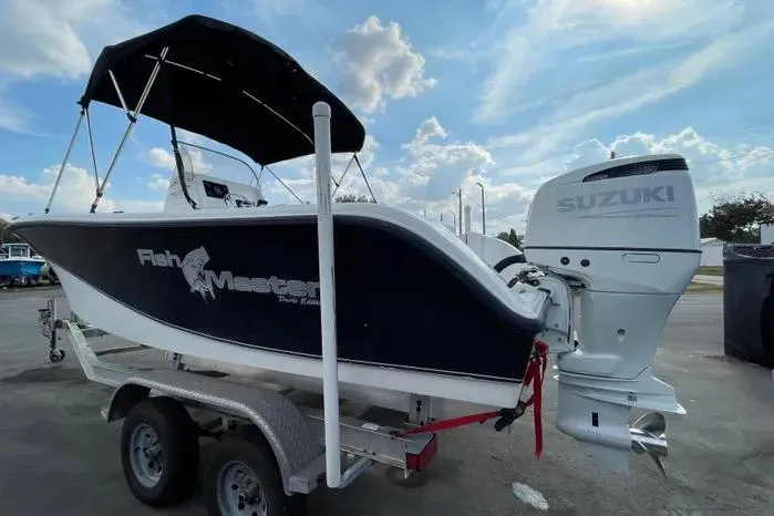 Slide: The Image of 2004 Kenner Fishmaster Travis Edition 220 boat on trailer under a sunny sky. - 7