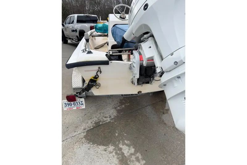 The Image of 1994 Chincoteague 16 boat on trailer with outboard motor, parked near a truck. - 1