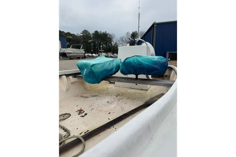 Slide: The Image of 1994 Chincoteague 16 boat interior with covered seats, parked near blue building. - 3
