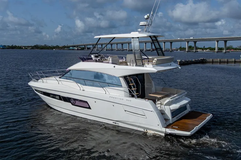 Slide: The Image of 2019 Prestige 460 yacht cruising on a calm river under a cloudy sky. - 10
