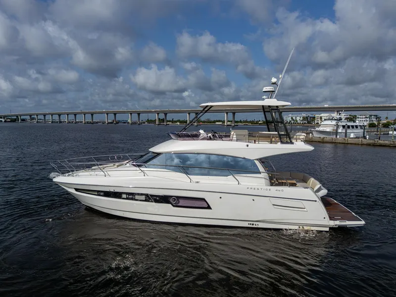 Slide: The Image of 2019 Prestige 460 yacht cruising on a calm river under a cloudy sky. - 11
