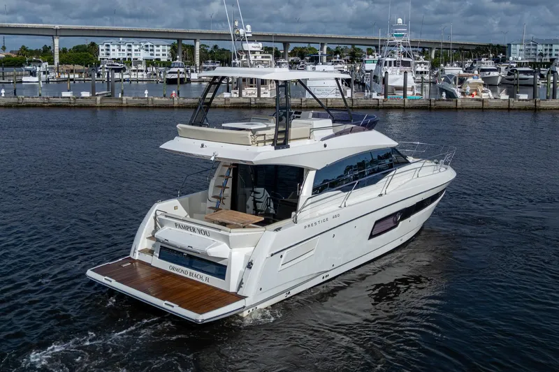 Slide: The Image of 2019 Prestige 460 yacht cruising in a marina, showcasing sleek design and luxury features. - 2