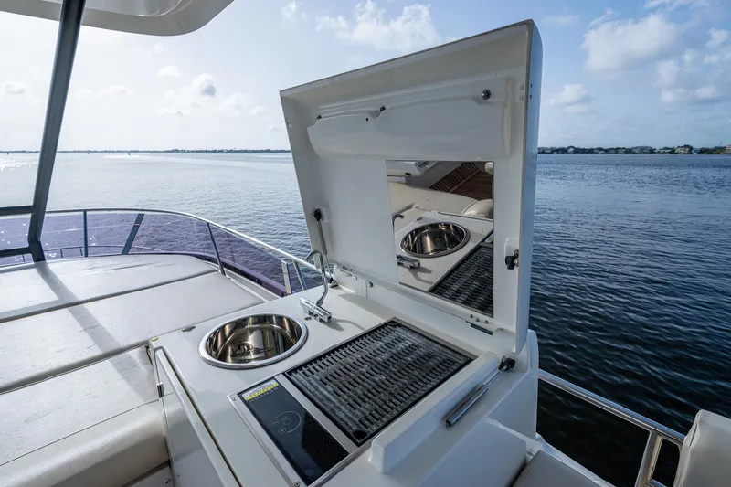 Slide: The Image of Outdoor kitchen on 2019 Prestige 460 yacht with grill and sink, overlooking serene water. - 32