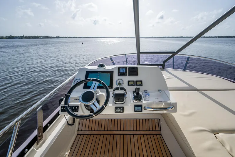 Slide: The Image of Helm of 2019 Prestige 460 yacht with wooden deck, overlooking calm waters. - 36