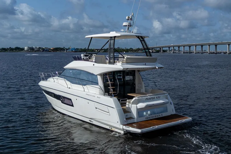 Slide: The Image of 2019 Prestige 460 yacht cruising on a calm river with a bridge in the background. - 9