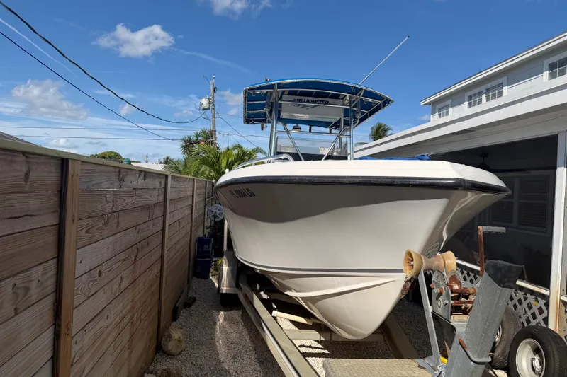 Slide: The Image of 2001 Bluewater 2350 CC boat on trailer beside wooden fence and house. - 2