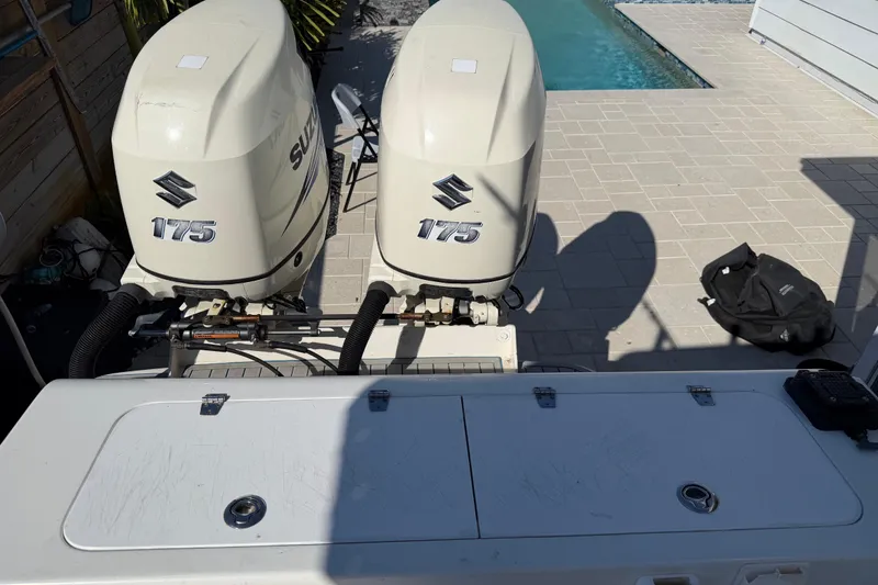 Slide: The Image of Twin Suzuki 175 outboard engines on a 2001 Bluewater 2350 CC boat by a poolside. - 23