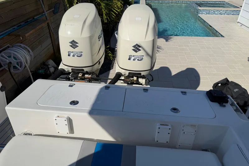 Slide: The Image of Twin Suzuki 175 outboard engines on a 2001 Bluewater 2350 CC boat by a poolside. - 24