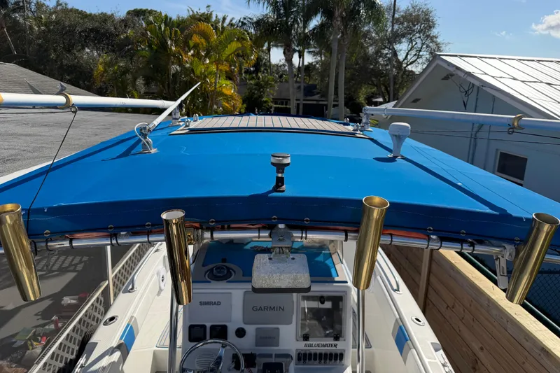 Slide: The Image of 2001 Bluewater 2350 CC boat with blue canopy and fishing rod holders. - 32