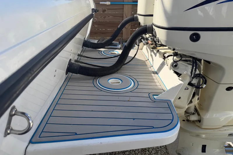 Slide: The Image of 2001 Bluewater 2350 CC boat deck with outboard motor and drainage hoses. - 8