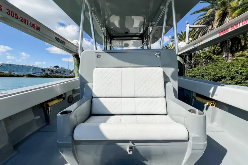 Slide: The Image of 2018 SeaVee 390Z boat interior with white seating, cup holders, and scenic waterfront view. - 15