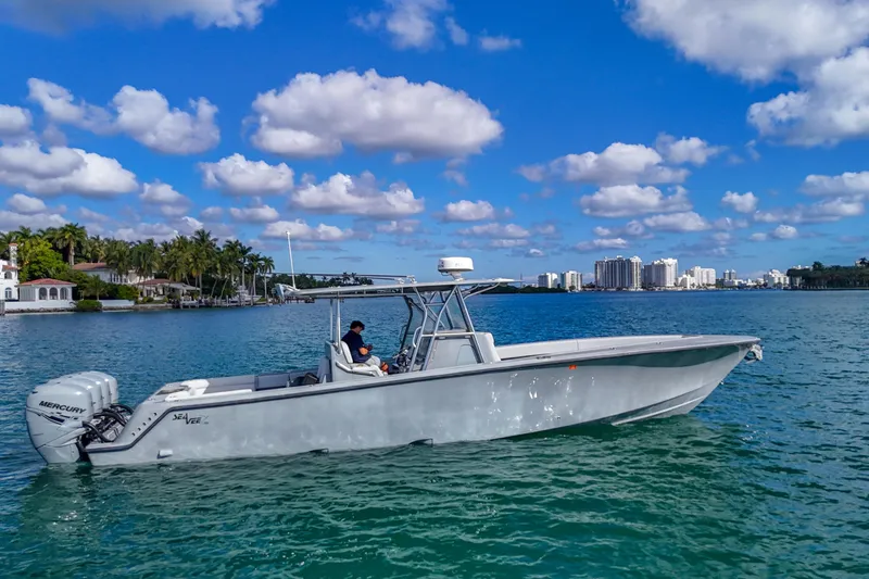 Slide: The Image of 2018 SeaVee 390Z boat cruising on a sunny day with city skyline in background. - 2