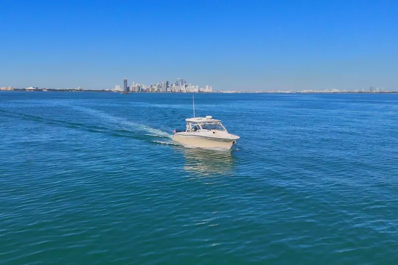 Slide: The Image of 2013 Grady-White Freedom 335 boat cruising on blue ocean with city skyline in background. - 5
