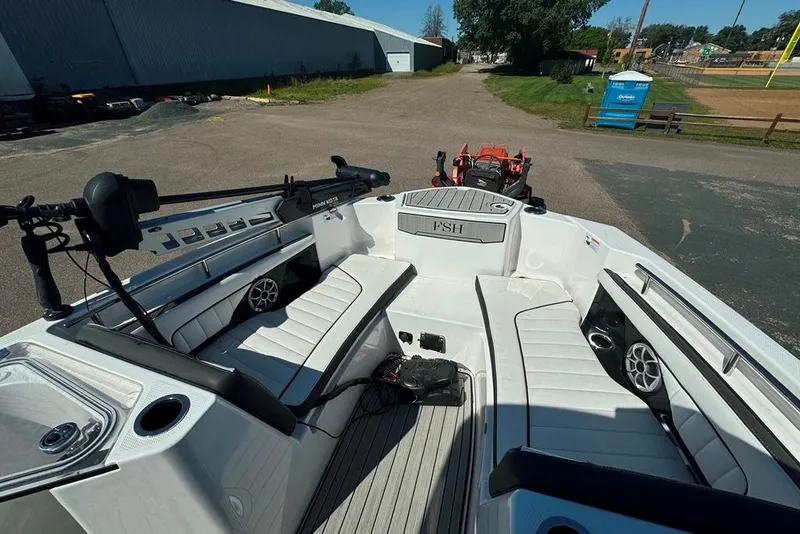 Slide: The Image of 2023 Yamaha Boats 255 FSH Sport E interior with seating and equipment, parked outdoors. - 10