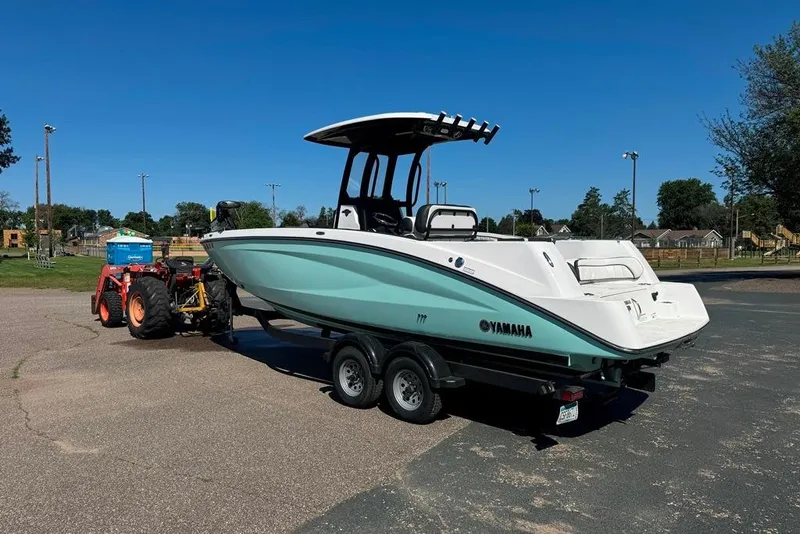 Slide: The Image of 2023 Yamaha Boats 255 FSH Sport E on trailer, parked outdoors under clear blue sky. - 16