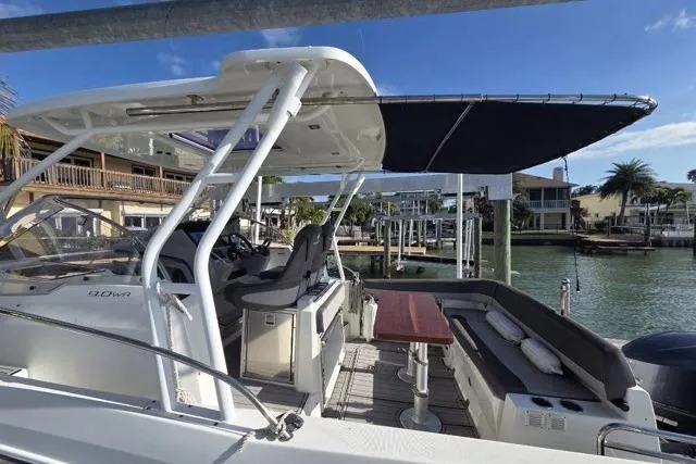 Slide: The Image of 2020 Jeanneau Leader 9.0 WA boat with canopy, docked by waterfront homes. - 4