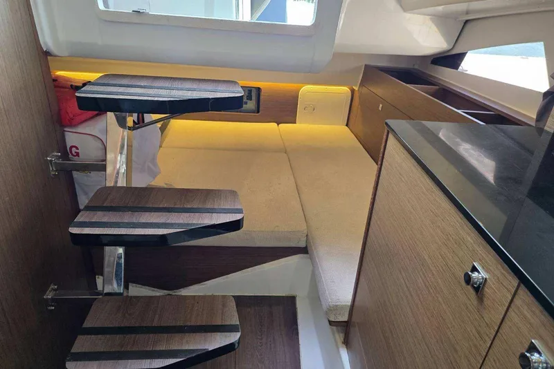 Slide: The Image of Interior of 2020 Jeanneau Leader 9.0 WA boat with wooden steps and cozy seating area. - 5
