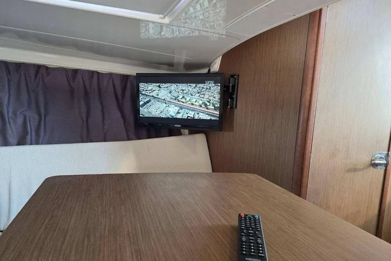 Slide: The Image of Interior of 2020 Jeanneau Leader 9.0 WA with TV and remote on table. - 7