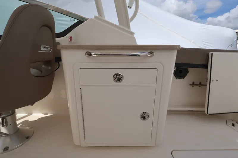 Slide: The Image of Interior view of a Boston Whaler 240 Vantage with a white cabinet and a brown seat. - 13
