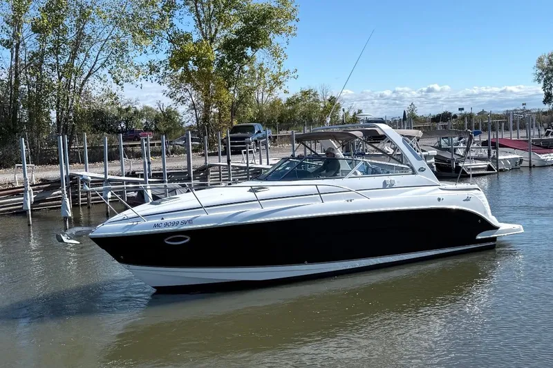 Slide: The Image of 2006 Rinker Fiesta Vee 300 boat docked on a calm lake with trees in the background. - 10